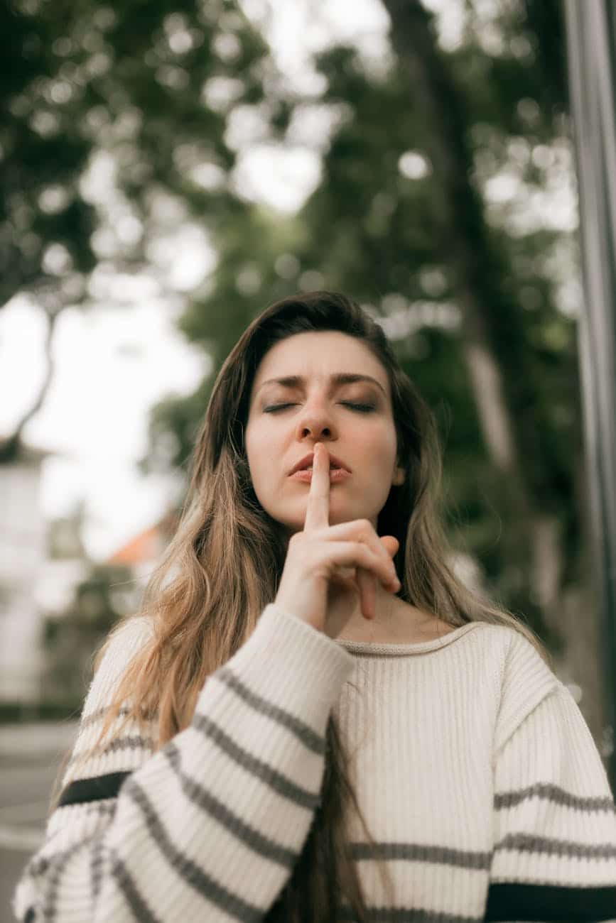 woman signaling for silence outdoors in fall
