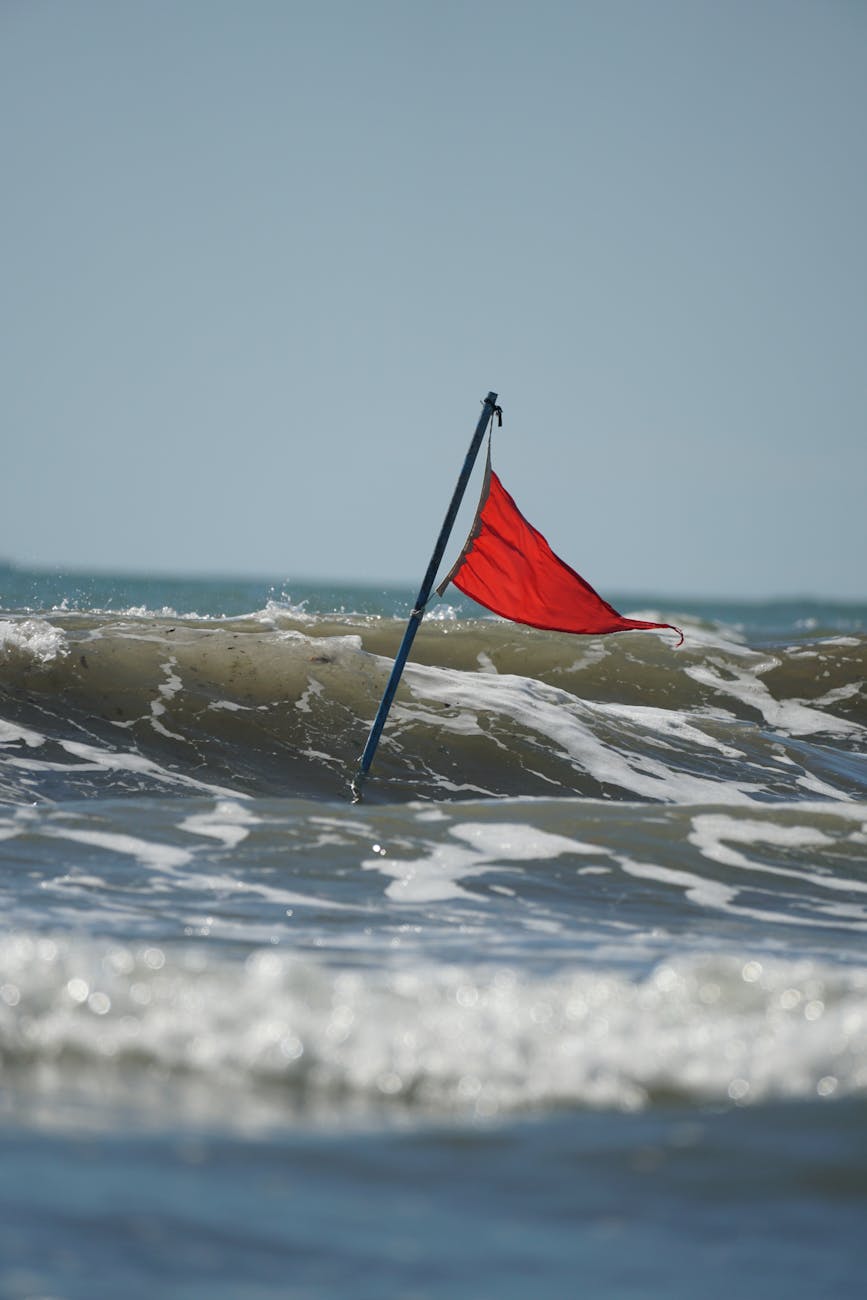 red flag waving on ocean waves under blue sky
