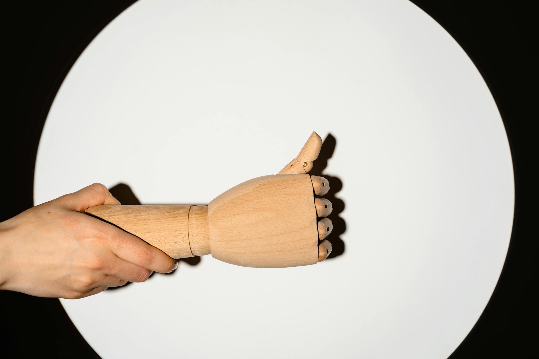 person holding a wooden hand with thumbs up gesture