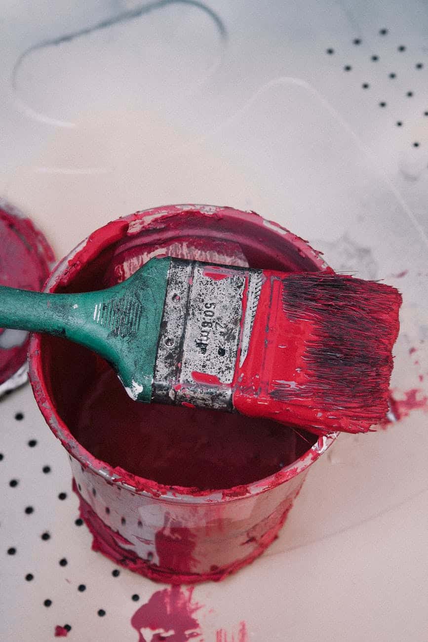 red paintbrush resting on open paint can